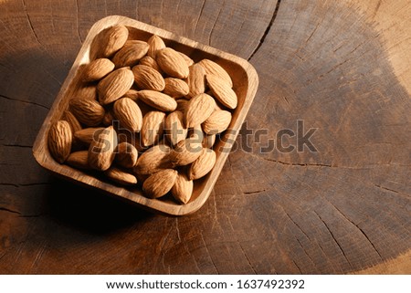 Almonds in a wooden bowl, on the wood background