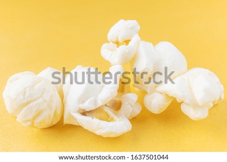 Close-up popcorn on a bright yellow background, macro photo. The concept of unhealthy delicious food, entertainment, a snack in the cinema. Copyspace.