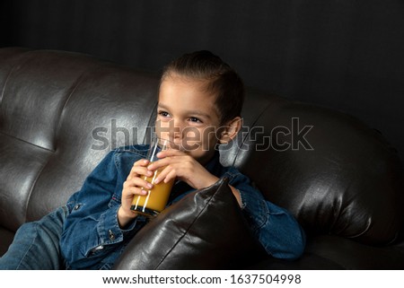 little boy is drinking fresh juice on black background	

