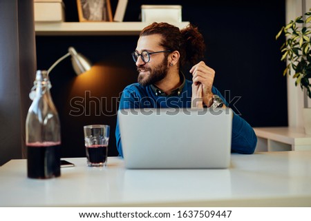 Handsome bearded caucasian freelancer sitting in his home office and looking trough window.