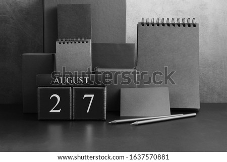 August 27th. Day 27 of month. Wood cube calendar with date month and day. Trendy classic black color. Lot of empty pages template for daily notes.