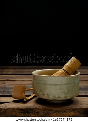 Green Matcha tea bamboo whisk in a bowl on wooden Preparation of powdered green tea