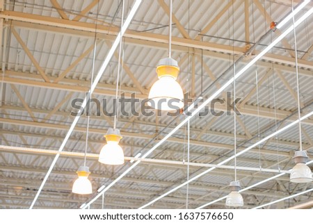 Ceiling with bright lamps in a modern warehouse. Image of bright light, a large space for trade, storage, commercial activity. Royalty-Free Stock Photo #1637576650