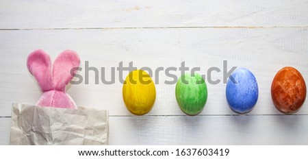 Easter eggs. Happy easter card. Multi-colored Easter eggs. Happy easter. Rabbit and eggs on a white wooden background. Banner, poster. Copy space