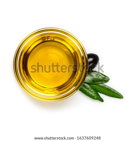 Olive oil. Extra virgin olive oil in glass transparent bowl with leaves and one black olive. Close up, isolated on white background.
