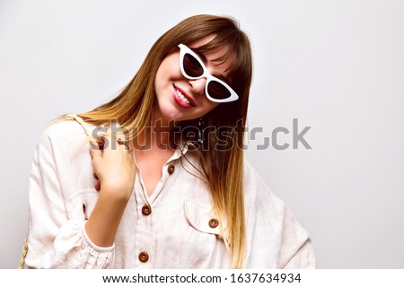 Cute indoor studio portrait of pretty hipster woman wearing boho shirt and vintage cat eye sunglasses,toned soft colors colors, smiling face.