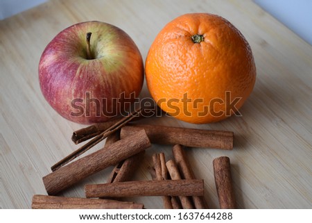 
apple orange and cinnamon on a wooden presentation board