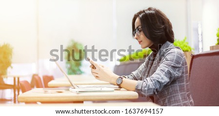 Searching for a job. Close-up photo of a freelancer woman in a smart outfit typing something on a smartphone while working in a public space.