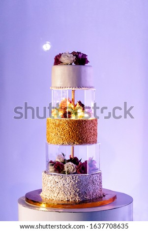 wedding cake three tiers white gold with flowers roses and stand on a pink fotne