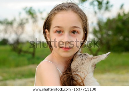 girl with baby goat on farm outdoors. Love and care. Village animals. happy child hugs goat, concept of unity of nature and man. Friendship of child and animals. Happy childhood. Girl and goat