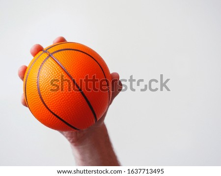 Mini basketball in a hand on a bright background.