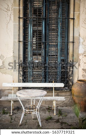Abandoned backyard with white bench, big woody window and table. Spain 