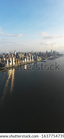 Aerial Cityscape- New York City Sunset- Panoramic Vertical Sunset Shot- Hudson River View Under Blue Sky with Clouds and Reflective Sun Rays off Skyscrapers
