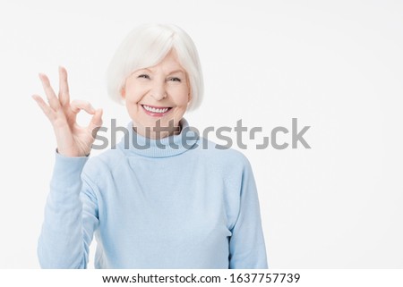 Senior beautiful woman doing ok gesture standing over isolated white background