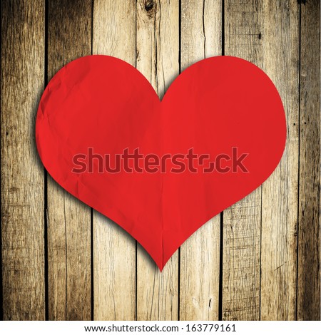 Red blank paper note with heart shape on grunge wooden background with copy space
