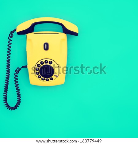 Yellow retro telephone on a blue background