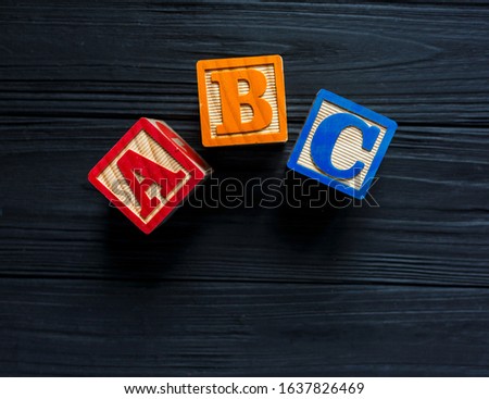 Wooden blocks with A B C letters, toys for creativity development on black background. Educational games for kindergarten, preschool kids.