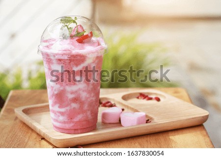 Healthy strawberry smoothie in a jar mug with candy in rustic wood.
