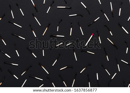 Many burnt matches and one unburnt match on a black background. Royalty-Free Stock Photo #1637856877
