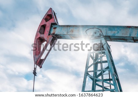 Oil pump jack rocking with pipeline in the background. Rocking machines for power generation. Extraction of oil. A pumpjack is the overground drive for a reciprocating piston pump in an oil well.