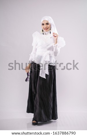 Beautiful female model wearing white blouse and black palazzo pants with hijab, isolated over white background. Stylish Muslim female hijab fashion lifestyle portraiture concept.