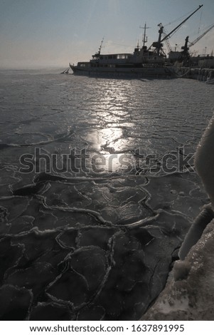 Frozen water of the Black Sea in the bay near the port in the city of Yevpatoriya (Crimea, Crimean peninsula).