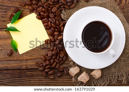 Cup of warm coffee, beans on  wooden surface. Free space for your text