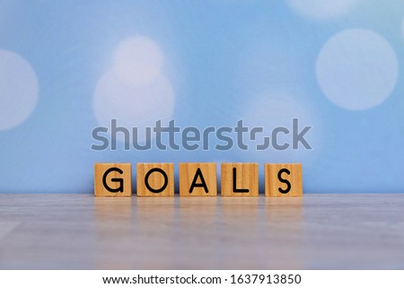 Inspirational quote - Goals. With single word on rustic wooden blocks  on soft blue bokeh background. Motivation word concept. Royalty-Free Stock Photo #1637913850