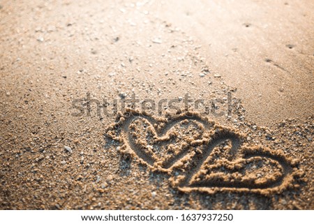 Draw two  heart in the sand.