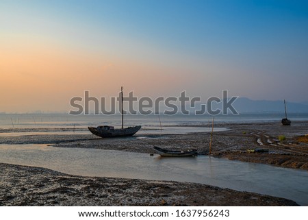 Fishing boats on the beach, sunset, clouds and sand make up a beautiful picture