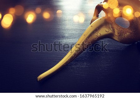 Venetian mask with a long nose over dark background