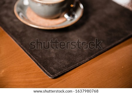 Leather rug on the table for crockery, coffee and just for hands. Gaming mat and for cafes, bars, restaurants. Cup of cappuccino on brown material