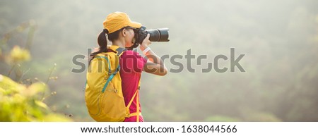 Woman photographer taking pictures in autumn forest