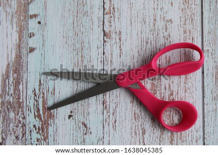 A pair of sharp,  pink scissors opened and ready to cut. 