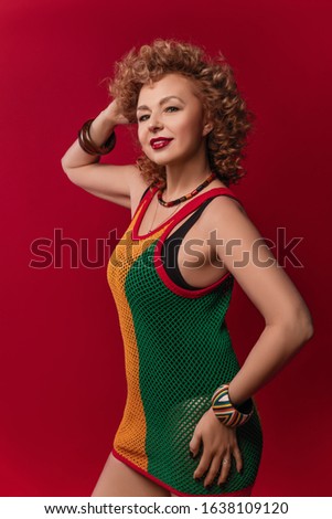 stylish portraits of a beautiful elderly woman with curly hair in a swimsuit and a dress from a grid in rasta colors on a red background