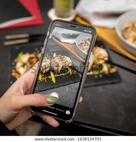 Girl taking picture of her chinese gyoza jiaozi dumplings food with smartphone 