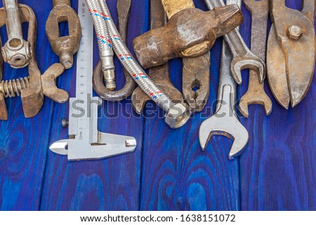 Many rusty old tools stacked after work on blue vintage wooden boards vertical orientation