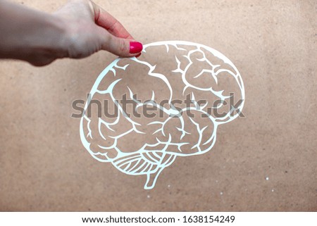 Woman holds the paper cutting brain in her arms. Paper art illustration. Origami on wooden background. 