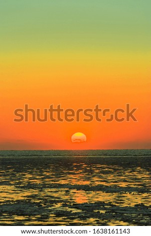 Sun of red glow far off horizon and blue sea