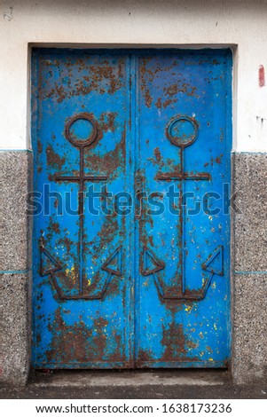 Blue rusted iron door with two symbols of anchors. Port of Essaouira, Morocco.