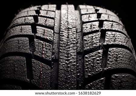 Brand new winter tire pattern on black background.