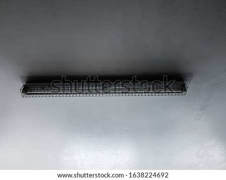 Picture of a long light bulb on the ceiling in a garage on a gray background in Thailand.