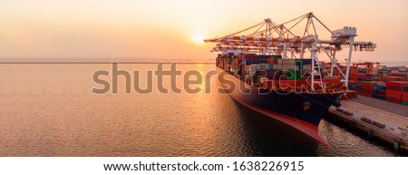 crane loading cargo container to container maritime ship in the international terminal container depot yard port  concept freight shipping by ship at sunrise .