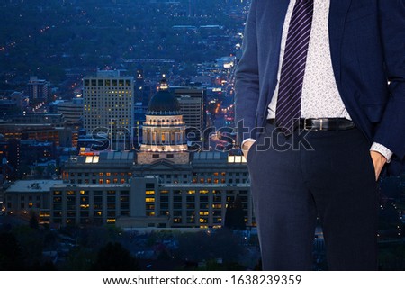 Businessman in suit with tie standing near the window of Salt Lake City downtown, Utah, USA