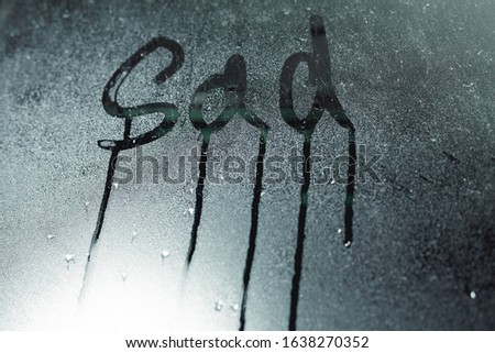 Window with raindrops. Stock photo the inscription "sad" in wet glass.