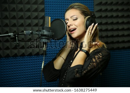 young girl singer in music recording studio. beautiful woman singing in a professional microphone