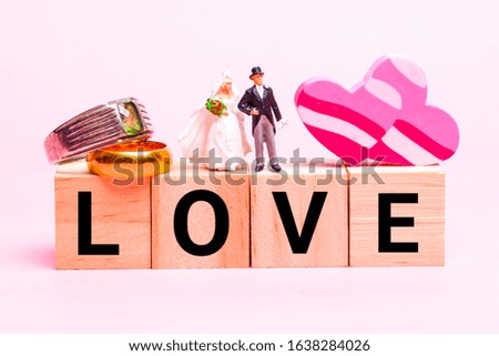 Closeup photo of married couple miniature with wedding ring, heart shape and LOVE wooden block.