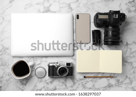 Flat lay composition with laptop, cameras and smartphone on white marble table. Designer's workplace
