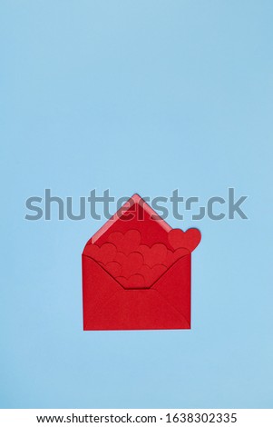 Red hearts flying out ot the red envelope on the light blue background. Valentine's Day greeting concept