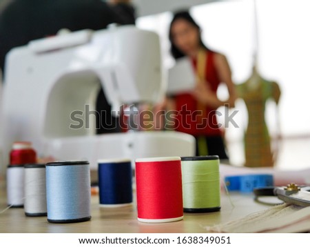 the sawing machine with sewing thread and the blur backgroun of defocused of european fashion designers  looking to color fabric textile at the designing studio office of tailor 